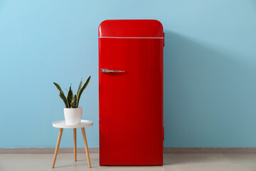 Canvas Print - Stylish retro fridge and table with houseplant near blue wall