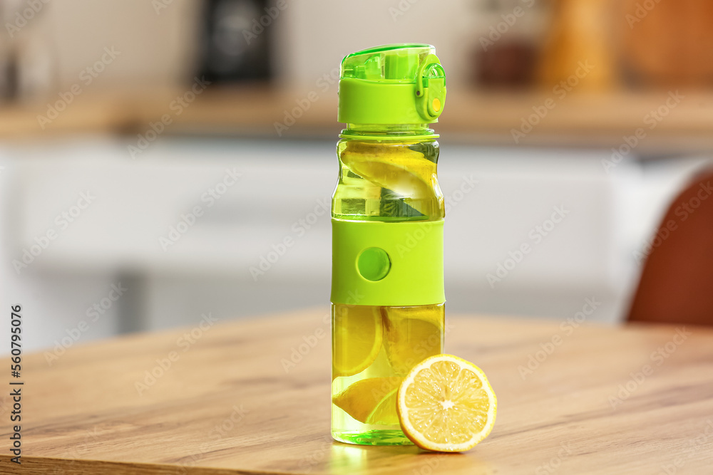Sports water bottle with lemon on table in kitchen