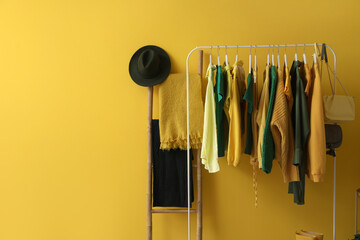 Wall Mural - Rack with stylish female clothes and accessories near yellow wall
