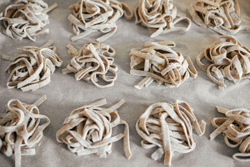 Homemade pasta. Dry fettuccine noodles in nests on baking tray close up. Making whole-grain pasta