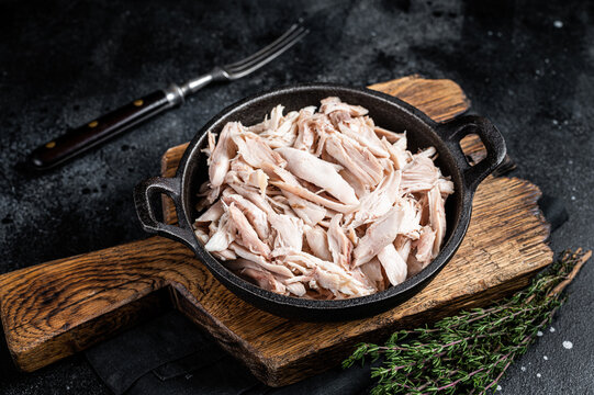 Sliced Pieces of chicken meat in a skillet, pulled chicken. Black background. Top view