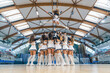 A group of cheerleaders are captured in a dynamic and athletic moment, performing a stunt by lifting one of their team members into the air. Showcasing energy, athleticism and unity in cheerleading.