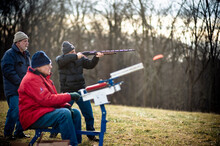 A Shooter Prepares As A Clay Target Flies Off A Skeet Machine.