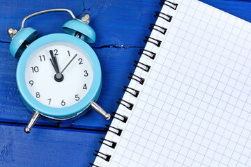 Wall Mural - Alarm clock on  table with empty notepad