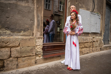 Wall Mural - Portrait of a happy young couple in love, a family hugging, holding hands in the city of Lviv in traditional Ukrainian shirts, holding hands. Young people hug in the old town of Lviv