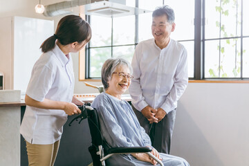 Poster - 車椅子に座る高齢者夫婦と介護士・理学療法士・介護スタッフの女性
