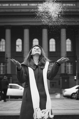 Wall Mural - Close up person throwing snow monochrome portrait picture. Closeup front view photography with city buildings on background. High quality photo for ads, travel blog, magazine, article