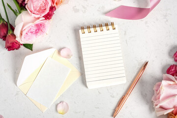 notebook with card and envelop mockup, roses and flower on marble table, wedding invitation and even