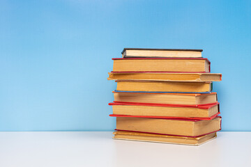 Stack of books in the colored cover lay on the wooden  table and blue backround. Education learning concept