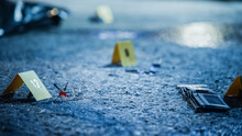 Bloodied Glasses, Bloody Knife And Empty Wallet, All Marked As Clues In A Murder Investigation. Close Up Low Angle Shot Of Evidence Scattered At Crime Scene. Forensics Work By Documenting Clues