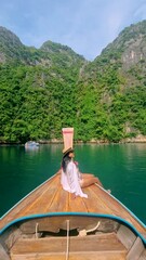 Wall Mural - Asian women in front of a Longtail boats and green blue turqouse lagoon at Pileh Lagoon Tropical Island of Koh Phi Phi Thailand