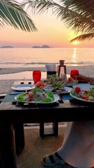 Wall Mural - Asian Thai women having a Romantic dinner on the beach in Thailand during sunset.