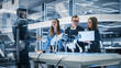© Gorodenkoff - Professional Multicultural Team of Female and Male Engineers Use Industrial Programmable Robot Animal in a Factory Development Workshop. Tech Facility with Machines, Computers and Research Equipment.