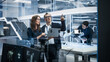 © Gorodenkoff - Portrait of Two Young Female and Male Engineers Use Laptop Computer to Connect, Analyze and Discuss How to Program a Robot Dog. Standing in High Tech Research Laboratory with Modern Equipment.