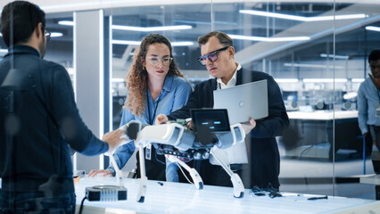 Aufkleber - Robotics Engineer, Project Manager and Machinery Operators Collaborate on a Robot Machine Project, Standing with Laptop Computer in Scientific Technology Lab. Young Team Developing an AI Robotic Dog.