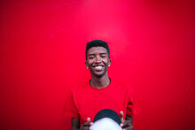 Black Teen Boy With Red Shirt Smiles On A Red Background