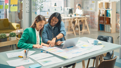 Wall Mural - Portrait of Two Creative Young Colleagues Consulting Each Other Using Laptop in Modern Office. Hispanic Male Supervisor Discussing Scheduling with Female White Head of Operations.