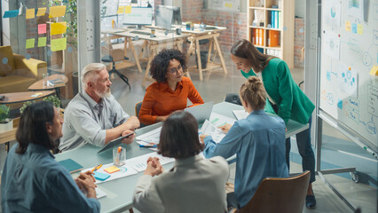 Wall Mural - Female Chief Analyst Holds Meeting Presentation for a Team of Economists. She Shows a Whiteboard with Growth Analysis, Charts, Statistics and Data, Answers Questions. People Work in Creative Office