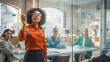 © Gorodenkoff - Black Young Woman Explaining Sales Growth Plan to a Diverse Team of Multiethnic People Using a Glass Board and a Marker. Female Specialist Using Mindmapping Technique to Brainstorm with Team at Office