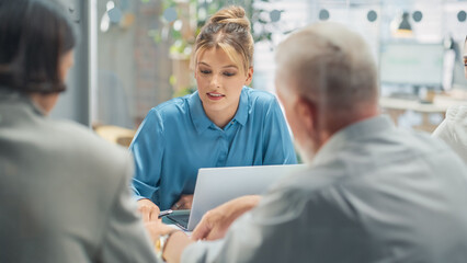 Leinwandbilder - In the Meeting Room Team of Entrepreneurs and Specialists sitting at the Conference Table Have Discussions about Statistics and Charts, Solve Problems, Led by Female Team Lead. They are Using Laptop