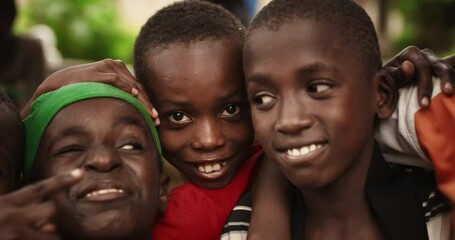 close up of the faces of a group of rural african young boys smiling, laughing and posing for camera
