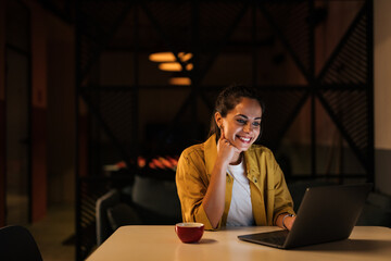 Smiling businesswoman, dressed casually, staying at the office late at night.