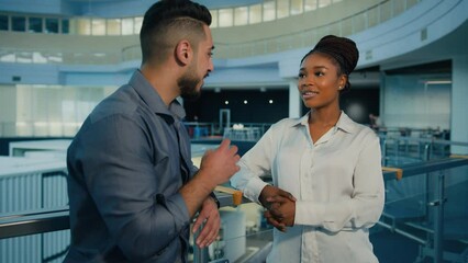 Wall Mural - Friendly diverse multiethnic business partners colleagues talking in office hall. African American woman businesswoman and Indian Arabian man businessman talk corporate discussion conversation at work