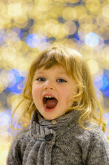 Wall Mural - Amazed portrait of a little girl in the middle of Christmas lights