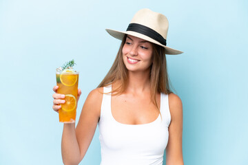 Wall Mural - Young beautiful woman holding a cocktail isolated on blue background with happy expression