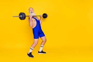 Poster - Full length portrait of sportive charismatic aged man press lifting barbell empty space isolated on yellow color background