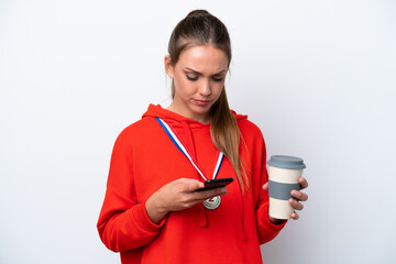 Wall Mural - Young caucasian woman with medals isolated on white background holding coffee to take away and a mobile