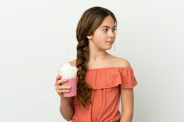 Wall Mural - Little caucasian girl with strawberry milkshake isolated on white background looking to the side