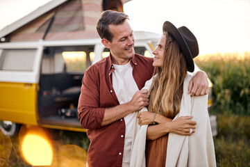 lovely cheerful young people couple enjoy the travel and active lifestyle, caucasian man and woman taking break on trip road together standing next to an old van outdoor. travel, adventure concept