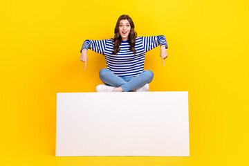 full length photo of excited positive person sit indicate finger empty space billboard isolated on y
