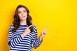 Photo of thoughtful doubtful young lady wear striped shirt pointing two fingers looking empty space isolated yellow color background