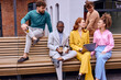 © Roman - Group portrait of interracial diverse young multiethnic businesspeople posing together sitting in bench, happy motivated multiracial employees show unity and success, teamwork, cooperation concept