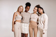 © Roman - Portrait of four beautiful diverse young women with perfect skin posing for camera while standing isolated over white studio background. Attractive ladies in casual clothes are friends