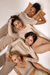 © Roman - Top view on four diverse ladies lying on floor in studio, calm and pacified, isolated. Young women of different appearance and ethnicity having close relationships, friendship, tolerance concept