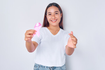 Wall Mural - smiling young blonde woman girl Asian wearing casual white t-shirt holding in hand pink silk ribbon and showing korean love sign isolated on white background. Breast Cancer Awareness concept