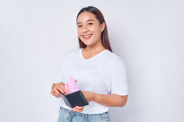 Wall Mural - portrait of smiling young blonde woman girl Asian wearing casual white t-shirt taking paper money rupiah from his wallet isolated on white background. people lifestyle concept