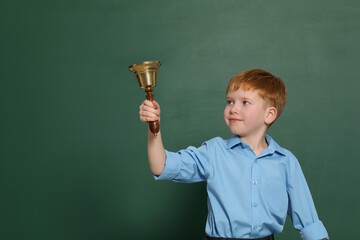 Wall Mural - Pupil with school bell near green chalkboard. Space for text