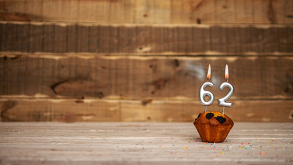 Scenery Festive wooden background happy birthday copy space. Anniversary background with number of burning candles and muffin. Beautiful brown from vintage boards background before a birthday 62