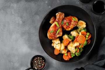 Wall Mural - Roasted Baked chicken legs drumsticks with vegetables on black plate on dark background. Meal, dinner diet concept, diet. Top view, copy space.