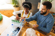 © Wavebreak Media - High angle view of biracial young couple sorting papers and plastics garbage in bins on table