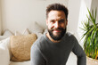 © Wavebreak Media - Portrait of smiling bearded biracial young man sitting on sofa in living room over wall, copy space