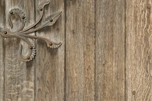 Fragment Of An Old Wooden Door With A Metal Decorative Hinge.
