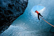 © Cavan Images - woma rappelling into glacier cave on Sólheimajökull glacier in Iceland