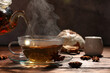 Pouring aromatic anise tea into glass cup on wooden table