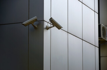 Modern CCTV cameras on a silver plastic wall. Concept of surveillance and area monitoring in real time.