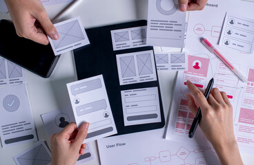 Close up ux developer and ui designer brainstorming about mobile app interface wireframe design on table.
